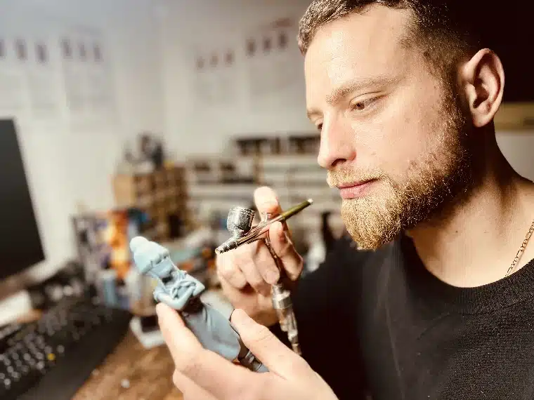 Dominique Perrin finissant une figurine à l'aérographe dans son atelier